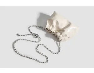 Detail shot of cream white ruched dumpling bag with metallic chain and sliding ball.