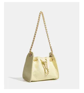 Detailansicht einer stilvollen gelben gesteppten Ketten-Kordelzug-Eimertasche mit goldener Hardware.