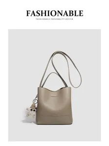 Detailed view of the grey bucket bag with shoulder strap and cute plush doll pendant.