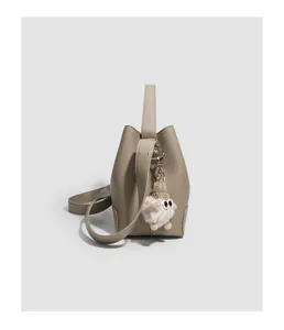 Grey leather bucket bag detail view with cute plush doll charm and comfortable shoulder strap