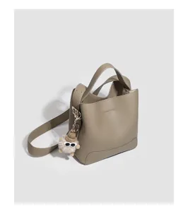 Detail shot of grey pu leather bucket bag handle and cute plush charm pendant accessory.