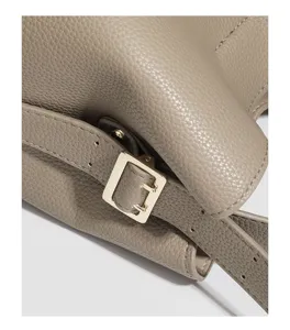Handbag detail close-up showcasing the golden metal buckle and textured leather strap.