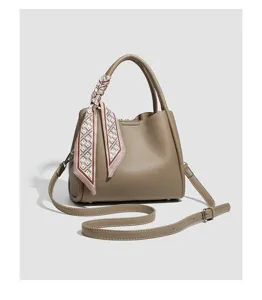 Detail van elegante taupe handtas, met stijlvolle sjaal op handvat en verstelbare riem.
