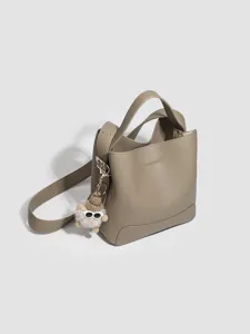 Women taupe bucket bag PU leather crossbody shoulder bag with cute fluffy plush doll pendant.