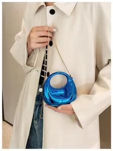 Detailed shot of trendy metallic blue mini handbag with gold chain strap, chic design.