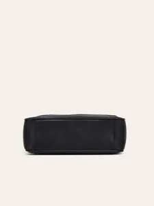 Black leather crossbody bag detail view showing fine texture, durable construction and sleek style.