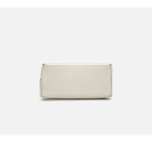 Bottom detail of a chic beige pebbled leather commuter handbag showing fine stitching and structure.