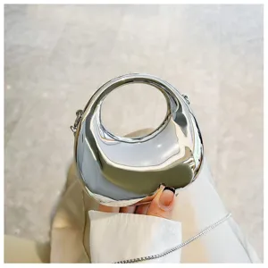 Close-up of metallic silver mini handbag with unique ring handle and chain strap detail.