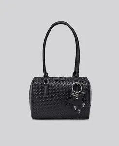 Close-up of black woven leather handbag detail featuring stylish star charm and dual handles.