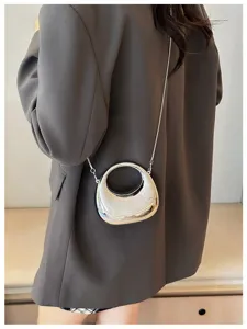 Silver metallic mini crossbody bag with sleek curve design and delicate chain strap for women.