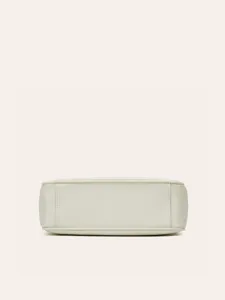 Detail view of minimalist leather crossbody bag bottom, showing neat stitching and clean design.