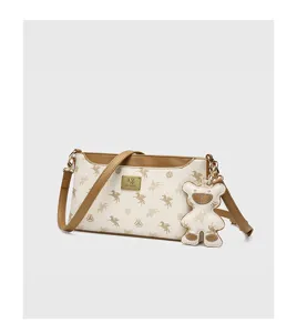 Detailed view of the stylish white and brown shoulder bag featuring cute bear charm.