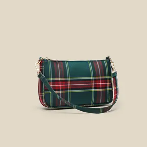 Detailed view of the red green plaid canvas shoulder bag showing fine strap and metal hardware.
