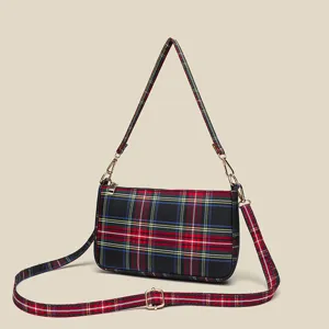 Red plaid canvas shoulder bag detail, featuring gold hardware and adjustable crossbody strap.