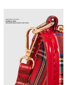 Détail de sac bandoulière à carreaux rouges avec fermoir doré et bord en cuir verni pour femmes.