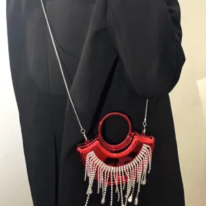Détail de sac de soirée rouge en acrylique, avec franges de cristaux et chaîne métal.