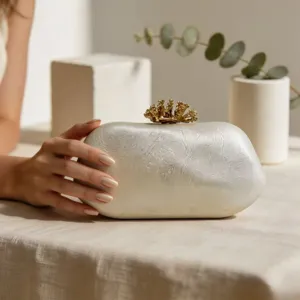 Detailaufnahme der unregelmäßigen Stein-Abendtasche mit goldenem Kronen-Verschluss.