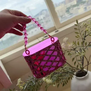 Gedetailleerd overzicht van de glanzende roze acryl strass cilinder handtas met handvat.