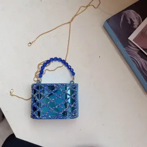 Gedetailleerd overzicht van luxe blauwe acryl strass cilindrische clutch tas.