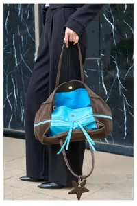 Gedetailleerd overzicht van bruine lederen shopper met blauwe voering en sterrenhangel.