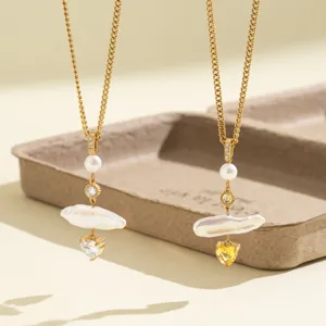 Detalle de collar de perlas de agua dulce barrocas con circonita de corazón en acero dorado.