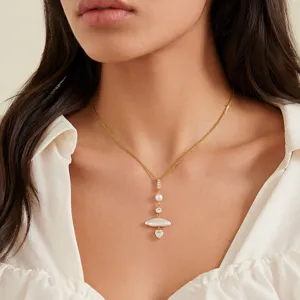 Vista detallada de un collar con perlas bañado en oro con circonita brillante y corazón.