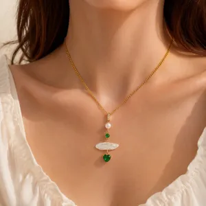 Primer plano detallado del collar elegante con perlas y colgante de circonita de corazón verde.