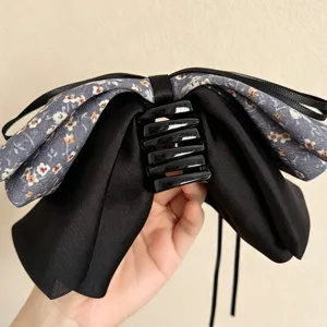 Nahaufnahme der Retro Blumen Schleife Haarklammer, elegantes schwarzes und graues Textildesign.