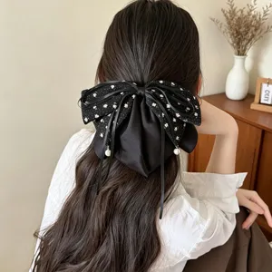 Detailansicht der eleganten schwarzen Blumen-Schleifen-Haarspange mit Perlenanhängern.