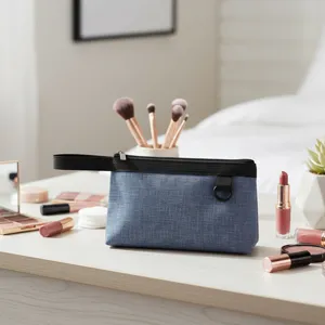 Primer plano de la bolsa de maquillaje de tela azul con cremallera negra en la mesa.