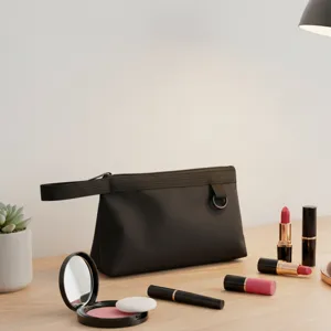 Vista detallada del neceser de maquillaje negro con asa y accesorios en el escritorio.