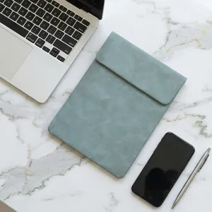 Minimalist blue-grey leather laptop sleeve detail shot on luxury marble desktop.