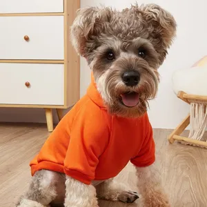 Detailed shot of an adorable dog wearing a warm bright orange fleece pet hoodie indoors.