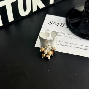 Vue détaillée d'une bague ouverte rétro large avec pendentif frangé de perles pour un style unique.