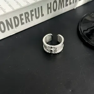 Gros plan d'une bague ouverte argentée style vintage avec design de croix et strass brillants.
