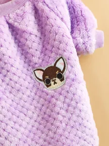 Close-up detail of soft purple coral fleece pet sweater featuring a cute puppy embroidered patch design.