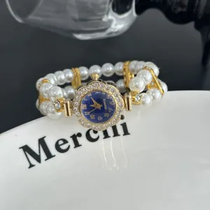 Vista detallada de un reloj de cuarzo con esfera floral de pedrería y pulsera de perlas.