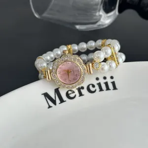 Vista detallada del elegante reloj de cuarzo con esfera floral de pedrería y pulsera de perlas.