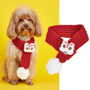 Red pet knitted scarf detail with festive lion dance plush decor and cozy white pompom.