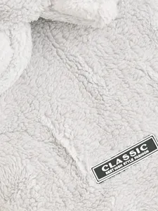 Gros plan de la texture de vetements pour animaux en peluche grise avec etiquette en cuir classique.