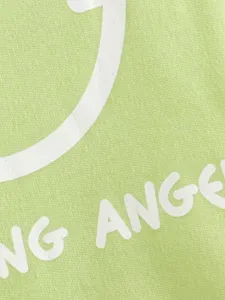 Close-up detail of green pet vest fabric, showing print texture and white smiley design.