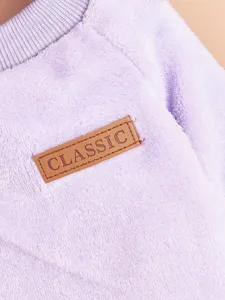 Close-up detail of soft purple pet fleece clothing featuring a brown classic leather label.