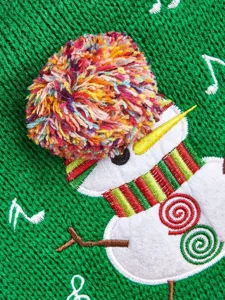Close-up of a green knit pet sweater featuring a cute 3D pom-pom snowman and festive details.
