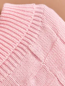 Pink knitted pet clothing fabric close-up with classic grid texture and high elasticity design.