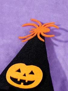 Halloween pet witch hat detail shot, black felt cone hat with orange pumpkin and spider decor.