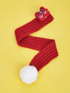 Detail view of red knitted pet scarf with festive lion dance design and white pom-pom.