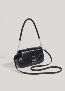 Close-up detail of the black leather shoulder bag showing unique metallic buckle and strap.