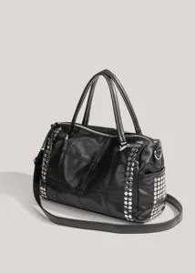 Détail de sac porté épaule matelassé noir avec clous métalliques et poignées doubles.