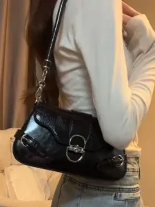 Black glossy patent leather baguette shoulder bag with metal lock and side buckle straps.