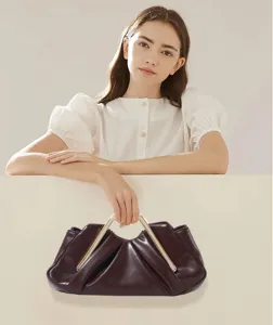 Detailed view of the dark brown soft leather pleated clutch bag with sleek metal top handle.